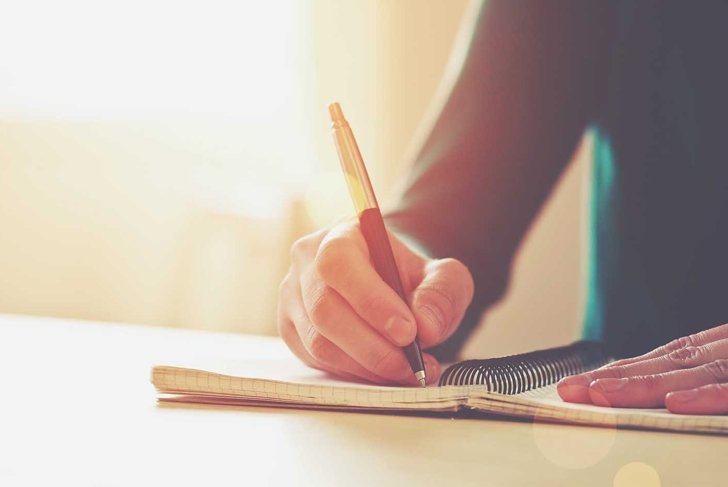 female hands with pen writing on notebook